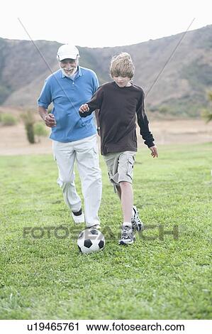 Stock Image - Grandfather and grand-son playing football. Fotosearch