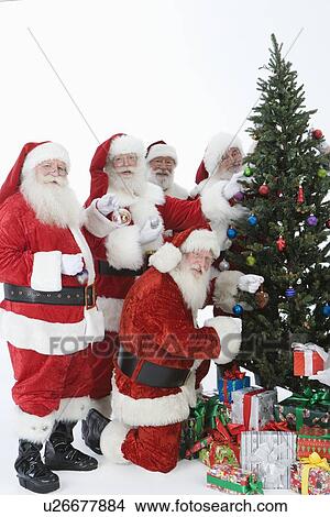 Picture - Group of men dressed as Santa Claus decorating Christmas tree. Fotosearch