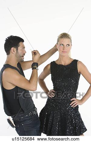 Picture - Hair stylist makes adjustments to model standing with hands on hips. Fotosearch