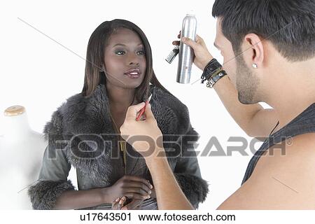 Stock Image - Hair stylist makes adjustments to model in fake fur jacket. Fotosearch