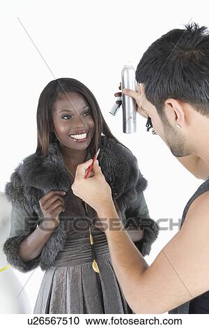 Stock Image - Hair stylist makes adjustments to model in fake fur jacket. Fotosearch