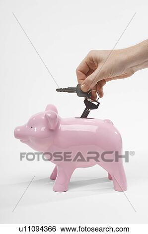 Stock Photograph - Hand Putting Car Keys in Piggy Bank. Fotosearch