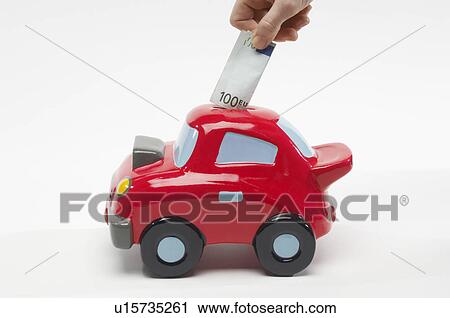 Stock Image - Hand Putting Money in Car Shaped Piggy Bank. Fotosearch