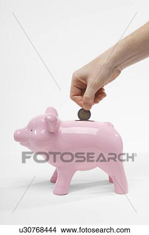 Picture - Hand Putting Money in Piggy Bank. Fotosearch