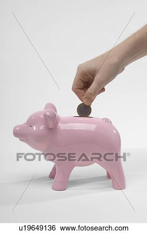 Stock Photograph - Hand Putting Money in Piggy Bank. Fotosearch