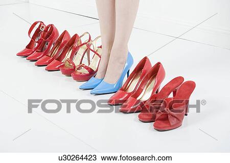 Stock Image - Line of red shoes with a woman standing in blue shoes. Fotosearch