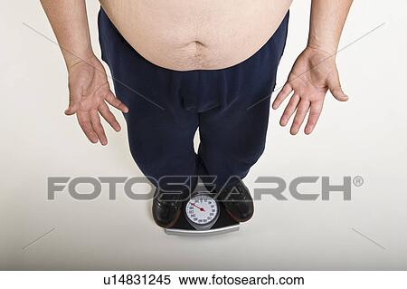 Stock Photography - Low section of man standing on bathroom scale. Fotosearch