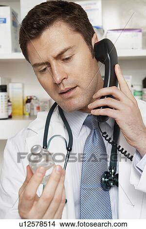 Picture - Male doctor using phone in hospital. Fotosearch