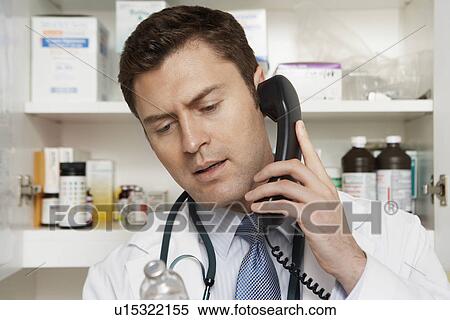 Stock Photography - Male doctor using phone in hospital. Fotosearch