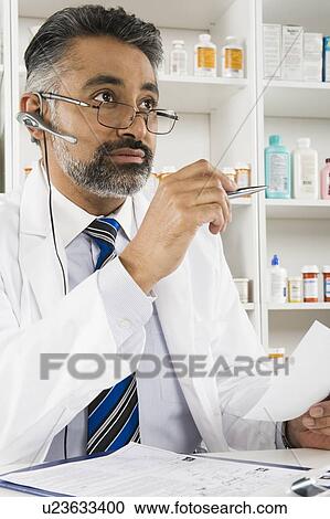 Stock Image - Male pharmactist working in pharmacy. Fotosearch
