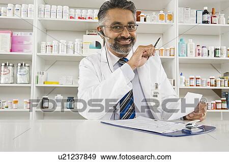 Stock Photo - Male pharmactist working in pharmacy. Fotosearch