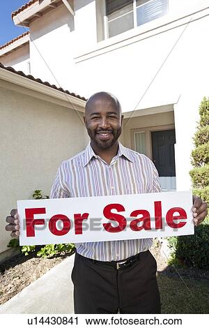 Stock Image - Man holding 'for sale' notice. Fotosearch