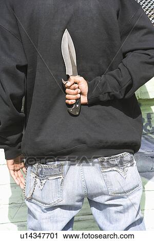 Stock Image - Man holding knife behind back. Fotosearch