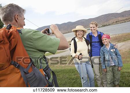 Man photographhs a mother, daughter and grand-daughter at lakeside together View Large Photo Image Stock Photo - Man photographhs a mother, daughter and grand-daughter at lakeside together. Fotosearch