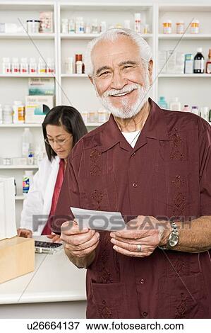 Stock Photo - Man picking up prescription drugs at pharmacy. Fotosearch