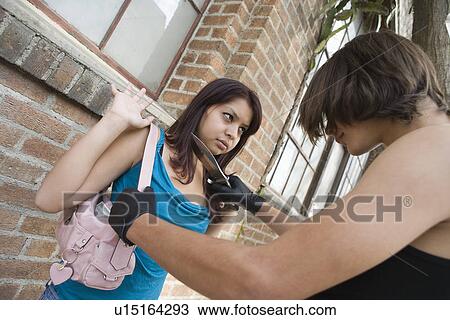 Stock Image - Man robbing young woman with knife. Fotosearch