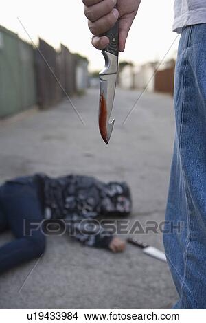 Man standing next to stabbed man lying on ground View Large Photo Image Picture - Man standing next to stabbed man lying on ground. Fotosearch