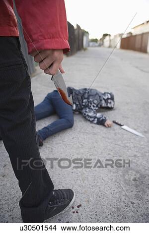 Man standing next to stabbed man lying on ground View Large Photo Image Picture - Man standing next to stabbed man lying on ground. Fotosearch