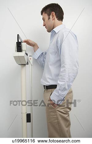 Man standing on weighing scales in hospital View Large Photo Image Stock Photograph - Man standing on weighing scales in hospital. Fotosearch