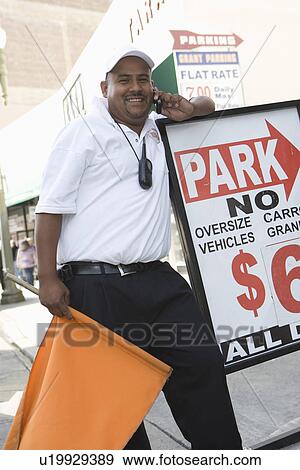 Stock Photo - Man using mobile phone near parking lot. Fotosearch