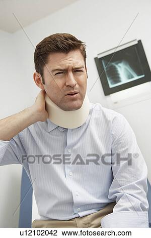 Stock Image - Man wearing neck brace in hospital. Fotosearch