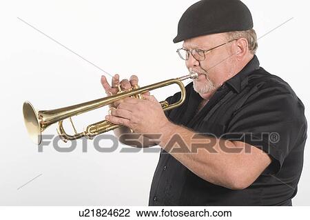Stock Image - Mature man in flat cap playing the trumpet. Fotosearch