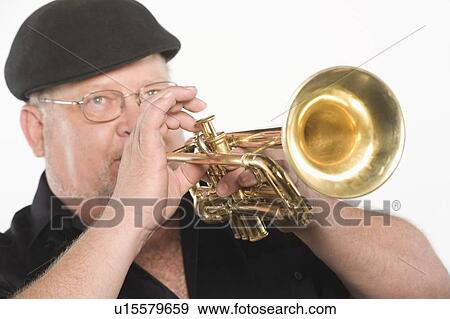 Stock Photo - Mature man in flat cap playing the trumpet. Fotosearch
