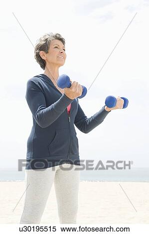 Stock Photography - Mature woman exercising with dumbbells. Fotosearch