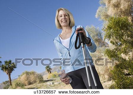Stock Photo - Mature woman holds walking poles. Fotosearch
