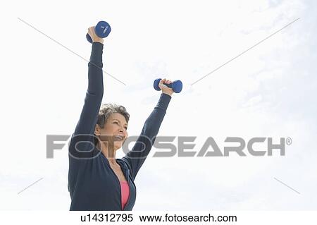 Stock Photography - Mature woman lifts dumbbells. Fotosearch