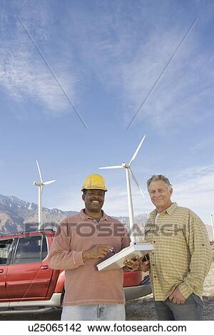Stock Image - Men working at wind farm. Fotosearch