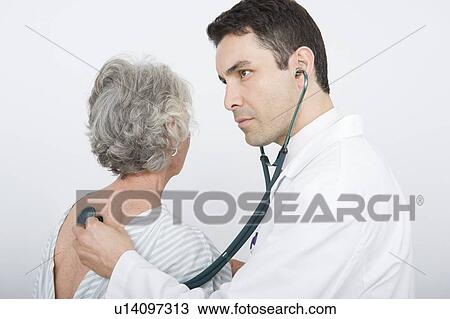 Mid adult doctor checks breathing of senior patient View Large Photo Image Stock Image - Mid adult doctor checks breathing of senior patient. Fotosearch