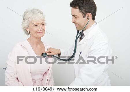 Stock Photo - Mid adult doctor checks breathing of senior patient. Fotosearch