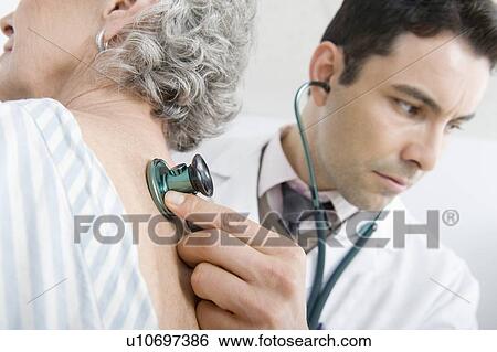 Mid adult doctor checks breathing of senior patient View Large Photo Image Stock Photograph - Mid adult doctor checks breathing of senior patient. Fotosearch