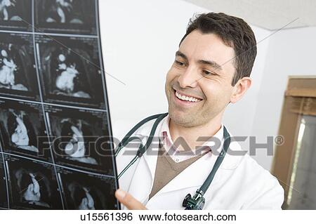 Mid adult doctor examines x-ray View Large Photo Image Stock Photograph - Mid adult doctor examines x-ray. Fotosearch