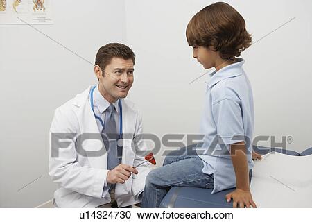 Stock Image - Mid-adult doctor examining boy with reflex hammer. Fotosearch