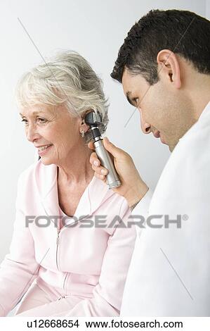 Picture - Mid adult doctor examining senior patient. Fotosearch