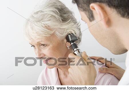 Stock Image - Mid adult doctor examining senior patient. Fotosearch