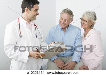 Mid adult doctor explains test results to senior couple View Large Photo Image Picture - Mid adult doctor explains test results to senior couple. Fotosearch