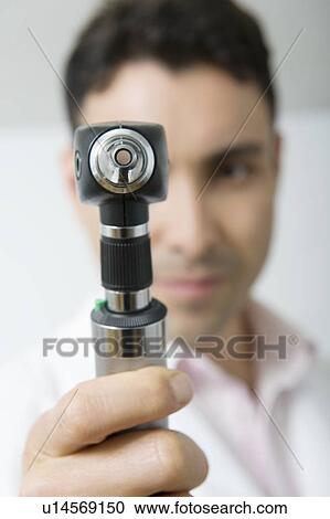 Mid adult doctor looks through sight testing equipment View Large Photo Image Stock Image - Mid adult doctor looks through sight testing equipment. Fotosearch