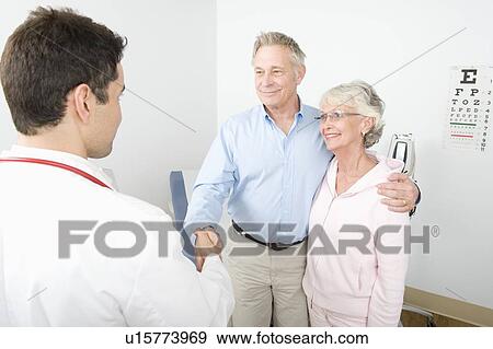 Stock Photo - Mid adult doctor shaking hand of senior man in couple. Fotosearch