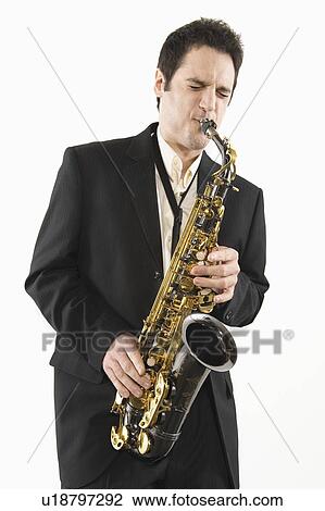 Stock Image - Mid adult man stands in suit playing the saxophone. Fotosearch