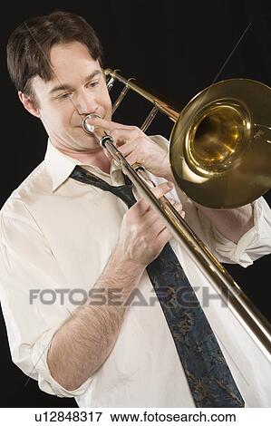 Stock Photo - Mid-adult man with open-collar shirt plays the trombone. Fotosearch