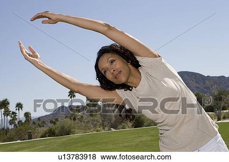 Stock Photo - Mid adult woman stretching arms over head. Fotosearch