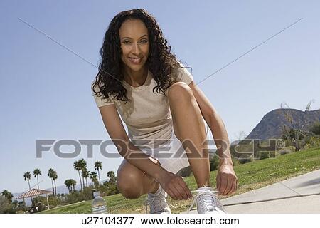 Mid adult woman ties shoelaces View Large Photo Image Stock Photo - Mid adult woman ties shoelaces. Fotosearch