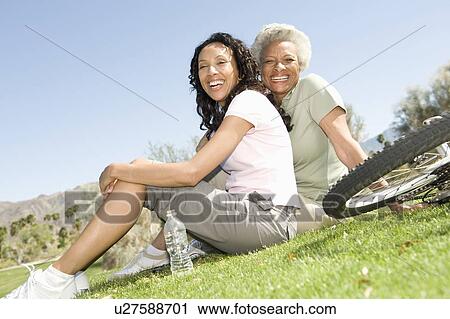 Mother and daughter sit in park with mountain bikes View Large Photo Image Stock Image - Mother and daughter sit in park with mountain bikes. Fotosearch
