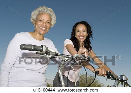 Picture - Mother and daughter sit on mountain bikes. Fotosearch