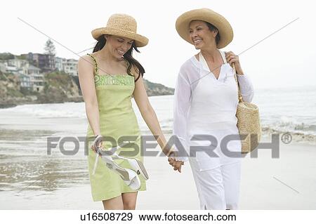 Mother and daughter walk along beach holding hands View Large Photo Image Stock Photo - Mother and daughter walk along beach holding hands. Fotosearch