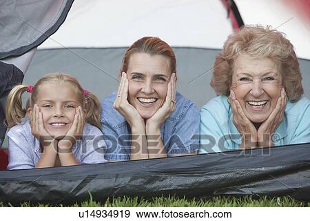 Stock Photo - Mother, daughter and grand-daughter lean on elbows, smiling from tent. Fotosearch