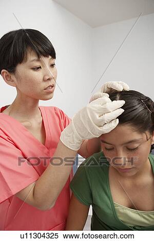 Nurse checking girls head in hospital View Large Photo Image Stock Photography - Nurse checking girls head in hospital. Fotosearch